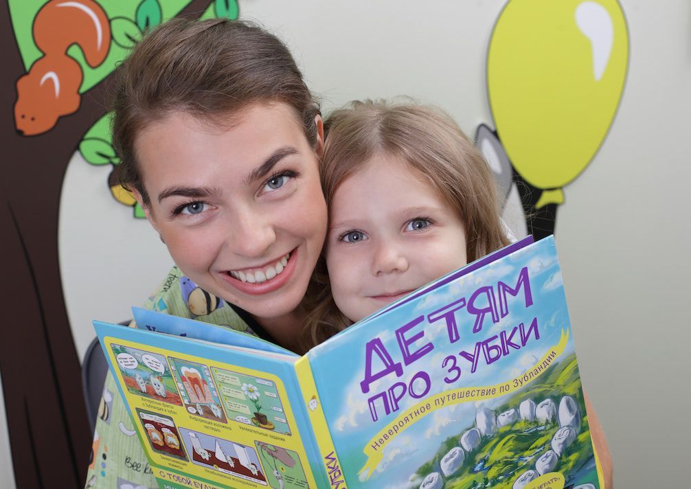 Девочка и стоматолог с книгой по гигиене полости рта